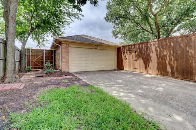 Garage featuring a gate and concrete driveway | Image 29