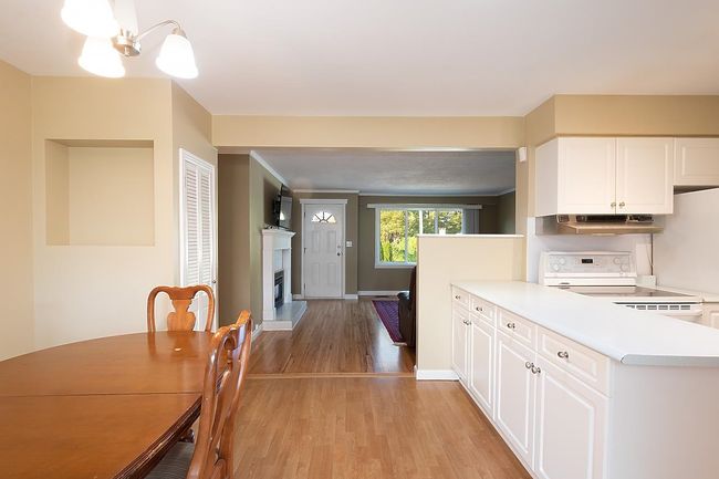 Kitchen featuring electric stove, under cabinet range hood, light countertops, a chandelier, and light wood-style flooring | Image 16