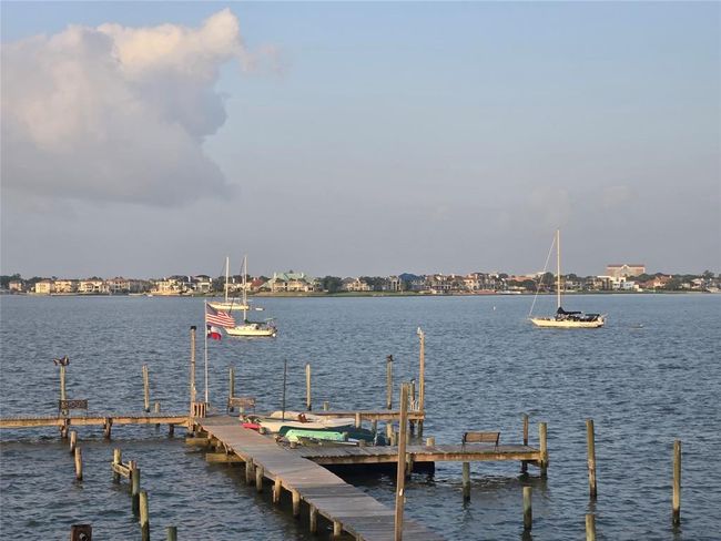 Scenic waterfront view with a wooden dock extending into calm waters, featuring sailboats and a backdrop of charming homes across the bay, perfect for boating enthusiasts. | Image 25