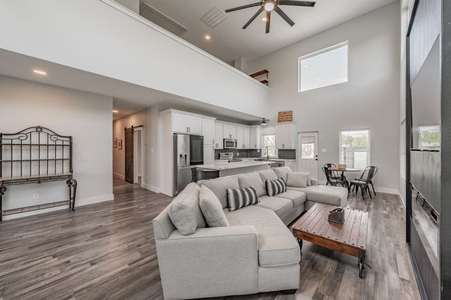 Living area featuring ceiling fan, a towering ceiling, dark wood-type flooring, baseboards, and recessed lighting | Image 19