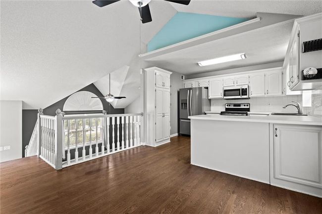 Kitchen featuring appliances with stainless steel finishes, ceiling fan, a peninsula, white cabinetry, and high vaulted ceiling | Image 15