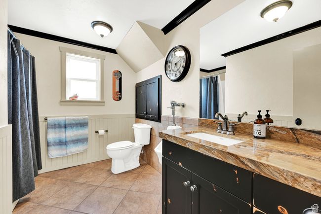 Bathroom featuring vaulted ceiling, vanity, ornamental molding, toilet, and tile patterned floors | Image 40