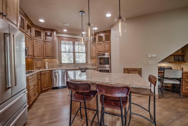 Kitchen with stainless steel appliances, an island, and kitchen desk area. | Image 9