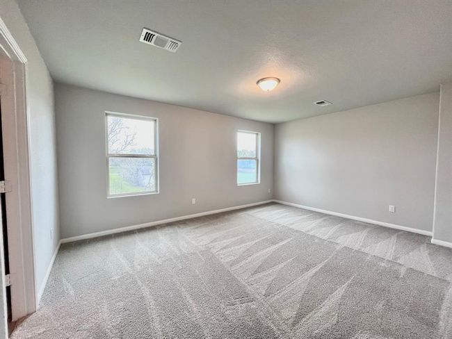 Spacious bedroom with plush carpet and abundant natural light, virtually staged for inspiration. | Image 24