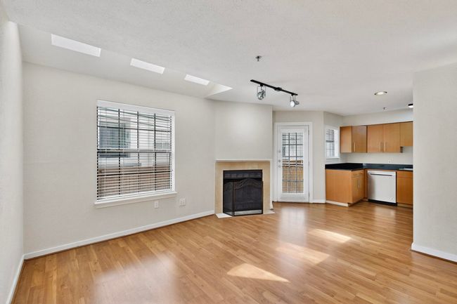 Unfurnished living room with a tiled fireplace, track lighting, and light wood-style floors | Image 5
