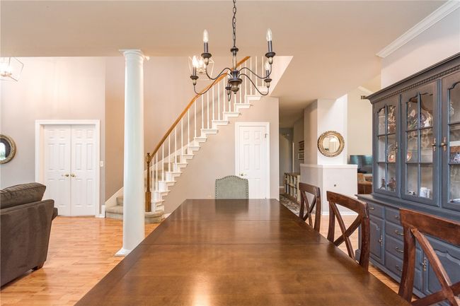 Dining space with a chandelier, stairs, light wood-type flooring, ornate columns, and crown molding | Image 5