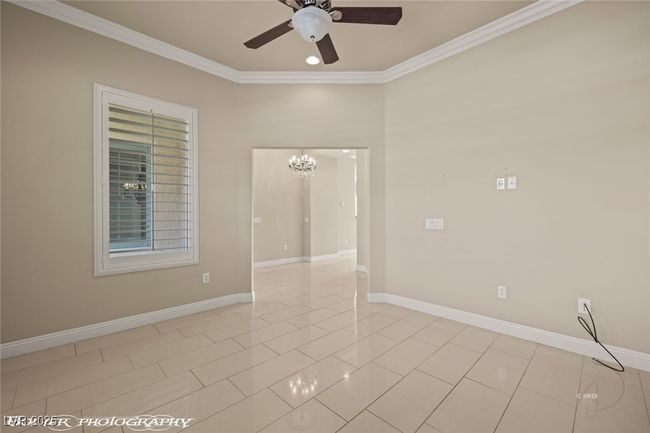 Empty room featuring ceiling fan with notable chandelier, baseboards, and ornamental molding | Image 9