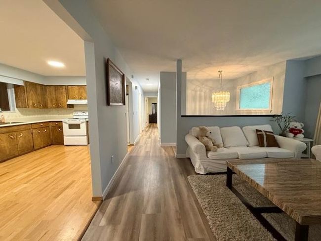 Living area featuring a chandelier, light wood-type flooring, and baseboards | Image 4