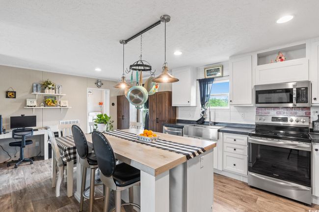 Kitchen with appliances with stainless steel finishes, a sink, a textured ceiling, white cabinets, and decorative backsplash | Image 14