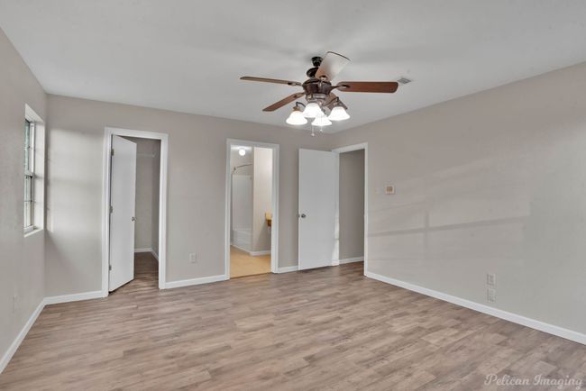bathroom, ceiling fan, a spacious closet, and light wood-type flooring | Image 17