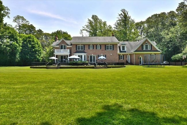 Back of property featuring a trampoline, a wooden deck, and a yard | Image 32