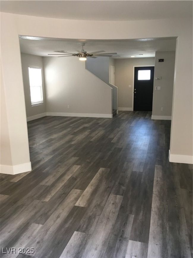 Unfurnished living room with baseboards, a ceiling fan, and dark wood-style floors | Image 4