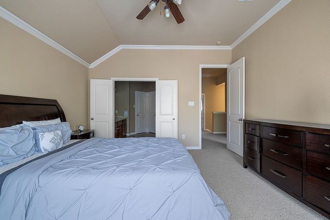 Bedroom featuring vaulted ceiling, ornamental molding, light carpet, ceiling fan, and baseboards | Image 14