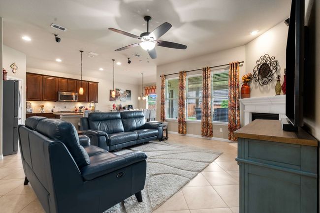 Living area with ceiling fan, light tile patterned floors, recessed lighting, and a fireplace | Image 9