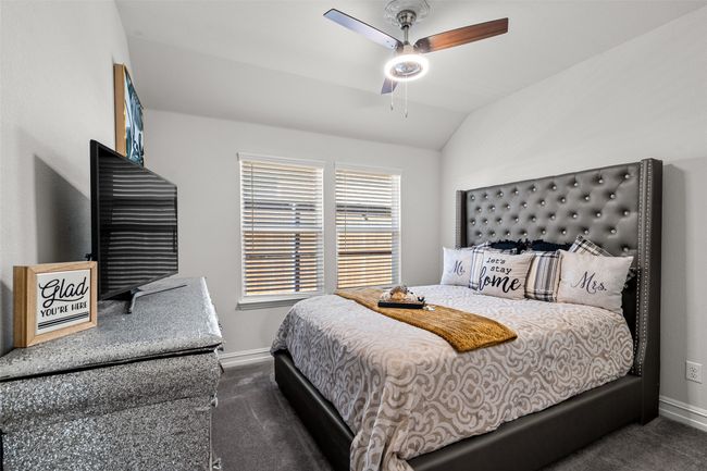 Bedroom one with ceiling fan, dark colored carpet, vaulted ceiling, and baseboards | Image 11
