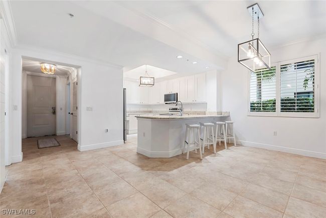 Kitchen with kitchen peninsula, stainless steel appliances, crown molding, decorative light fixtures, and white cabinets | Image 8