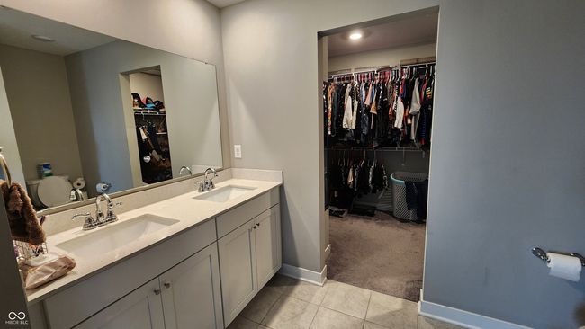 bathroom with double vanity, tile patterned floors, and a spacious closet | Image 15