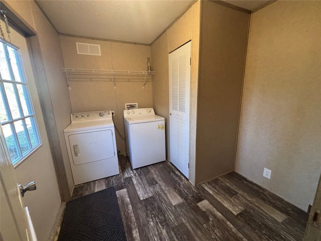 Washroom with dark wood finished floors, visible vents, separate washer and dryer, laundry area, and plenty of natural light | Image 19