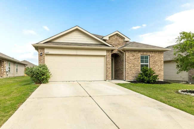 View of front facade with driveway, a garage, a front lawn, and brick siding | Image 34