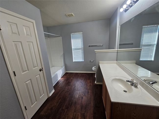 Bathroom with vanity, wood finished floors, shower / washtub combination, and a textured ceiling | Image 17