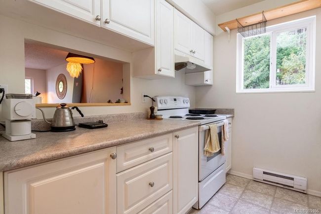 Kitchen featuring baseboard heating, white cabinets, white electric range, and a healthy amount of sunlight | Image 8