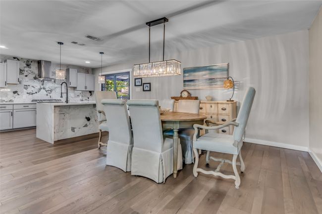 Dining room with light wood-style floors and a chandelier | Image 10