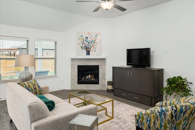 Living room with baseboards, ceiling fan, vaulted ceiling, a tile fireplace, and wood finished floors | Image 19