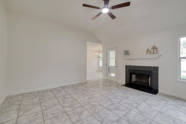 Unfurnished living room featuring healthy amount of natural light, a chandelier, ceiling fan, a tile fireplace, and vaulted ceiling | Image 9