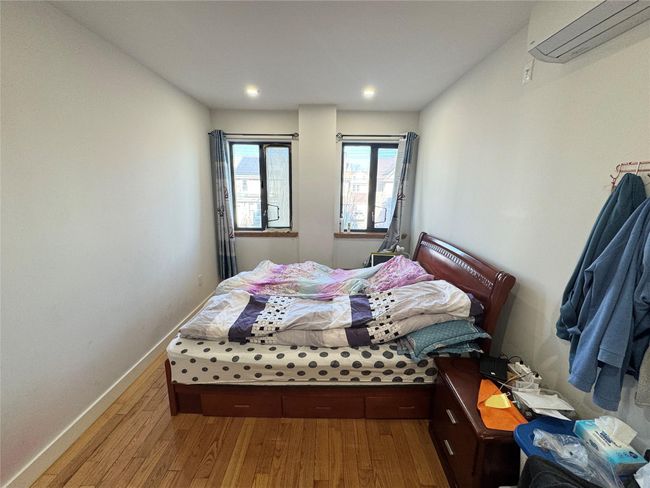 Bedroom with hardwood / wood-style flooring and an AC wall unit | Image 7