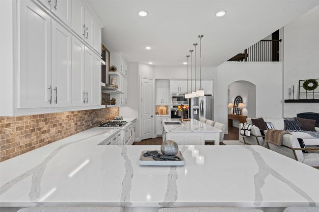 Kitchen featuring stainless steel appliances, arched walkways, decorative backsplash, dark wood finished floors, and light stone countertops | Image 13