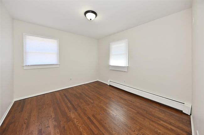 Empty room with dark wood-style floors, baseboard heating, and baseboards | Image 17