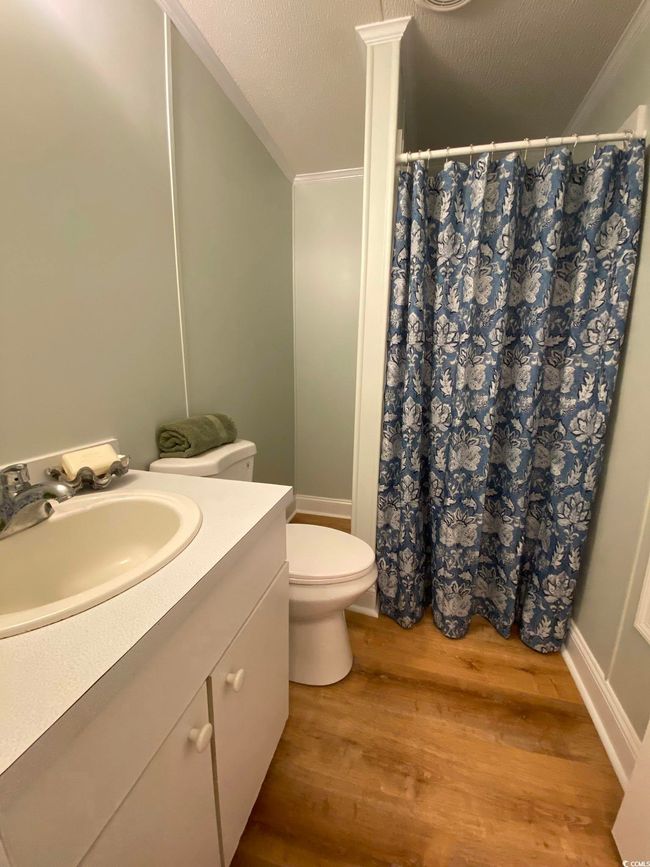 Full bath with ornamental molding, wood finished floors, vanity, toilet, and curtained shower | Image 26