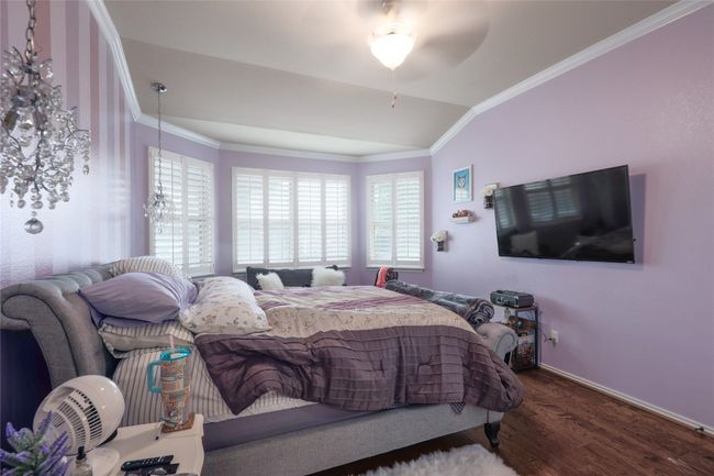 Bedroom with ornamental molding, wood finished floors, lofted ceiling, and baseboards | Image 14