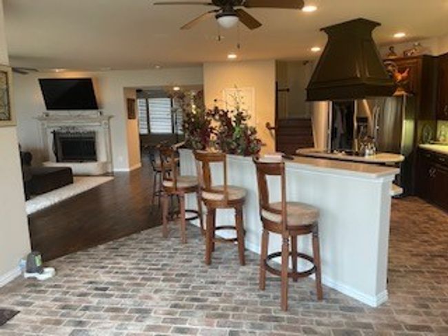 Kitchen with island range hood, brick floor, dark brown cabinets, and ceiling fan | Image 12