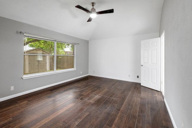 Empty room with hardwood / wood-style floors, baseboards, a ceiling fan, and vaulted ceiling | Image 19