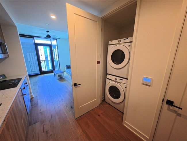 Laundry area featuring stacked washer and clothes dryer, dark wood-style flooring, ceiling fan, and recessed lighting | Image 9