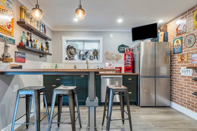 Bar with crown molding, stainless steel appliances, brick wall, light wood-type flooring, and indoor wet bar | Image 29