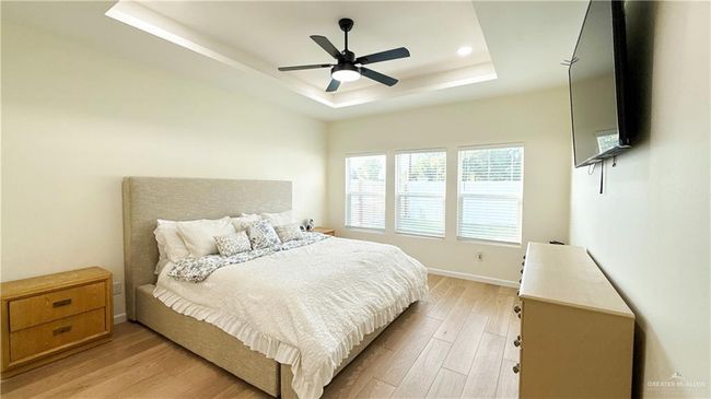 Bedroom featuring a tray ceiling, light wood-style flooring, recessed lighting, and a ceiling fan | Image 13