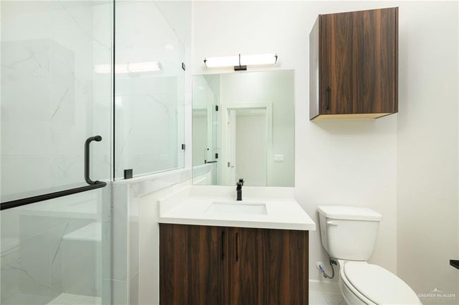 Bathroom featuring a marble finish shower, toilet, and vanity | Image 13