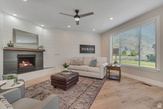 Living area featuring a ceiling fan, recessed lighting, a warm lit fireplace, and wood finished floors | Image 5