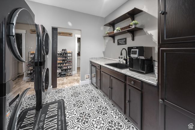 laundry room featuring a sink, stacked washer / dryer, dark brown cabinets, open shelves, and beverage cooler | Image 48