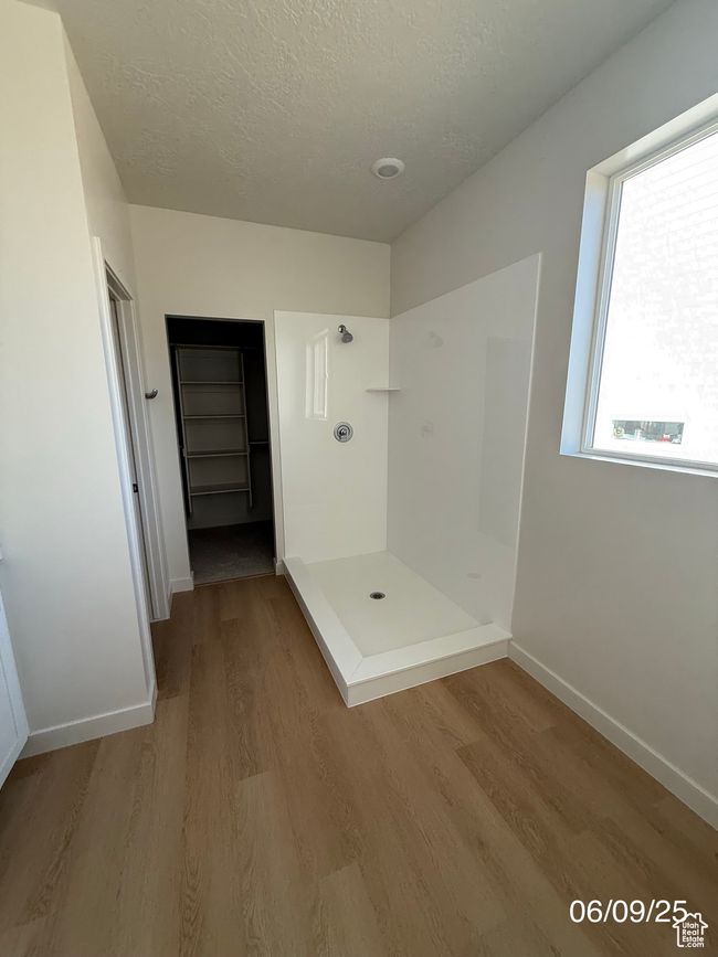 Full bath featuring a stall shower, wood finished floors, baseboards, and a textured ceiling | Image 8