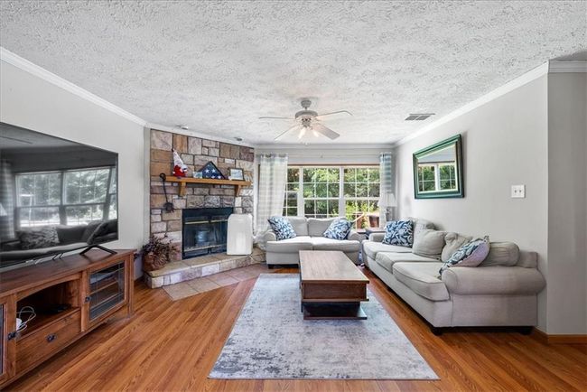 Living room featuring a textured ceiling, visible vents, crown molding, wood finished floors, and a ceiling fan | Image 6