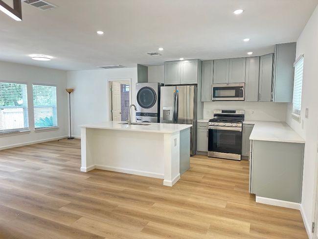 Kitchen featuring appliances with stainless steel finishes, stacked washer and clothes dryer, gray cabinetry, plenty of natural light, and recessed lighting | Image 8