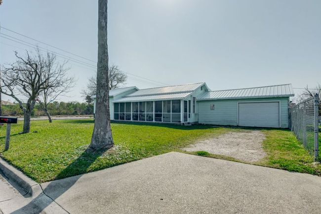 View of front of house featuring a sunroom, metal roof, dirt driveway, a garage, and a front lawn | Image 29