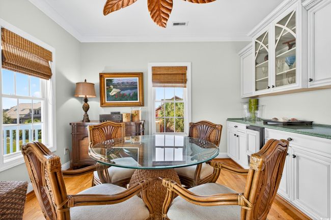 Dining area featuring crown molding, a bar, and light wood-style flooring | Image 7