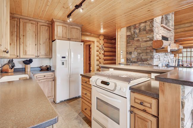 Kitchen featuring white appliances, log walls, wood ceiling, rail lighting, and light brown cabinets | Image 12
