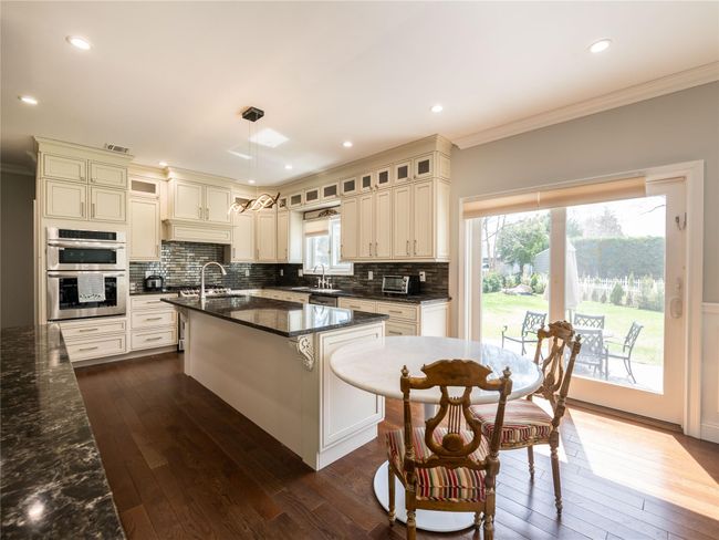 Kitchen featuring stainless steel double oven, a sink, dark wood-type flooring, and ornamental molding | Image 9
