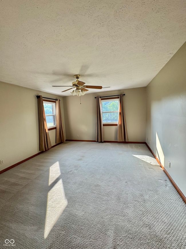 unfurnished room with light carpet, baseboards, ceiling fan, and a textured ceiling | Image 59