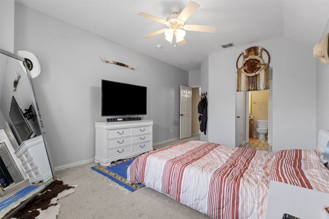 Bedroom with light colored carpet, ceiling fan, ensuite bathroom, baseboards, and lofted ceiling | Image 34